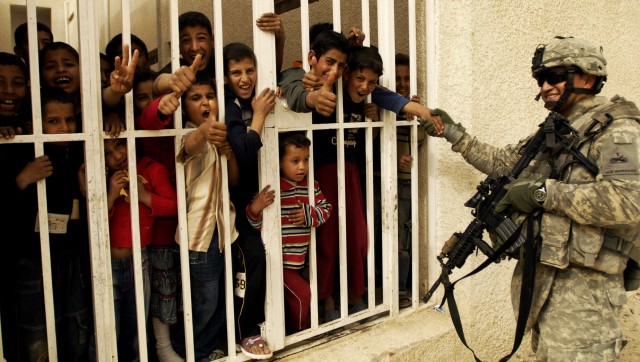 BAGHDAD - Iraqi children cheer, smile, give the "thumbs-up" sign and shake hands with Staff Sgt. Jorge Cornejo, of Brentwood, N.Y., Headquarters and Headquarters Company, 2nd Brigade Combat Team, 1st Armored Division, Multi-National Division -...