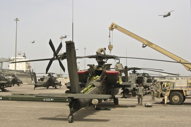 Three CH-47F Chinook helicopters fly from port in Kuwait headed to Camp Buehring as mechanics from the 1st Air Cavalry Brigade, 1st Cavalry Division finish reassembling the rotors to an AH-64D Apache attack helicopter, May 2. Soldiers, pilots and...