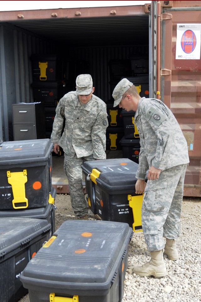 BAGHDAD - Spc. Adam Eddy (left), and Spc. Shane Paul, unload boxes of equipment from their unit's storage container shortly after arriving at Forward Operating Base Falcon, May 8. Both Soldiers are natives of Denver, Colo., and members of Company B, ...
