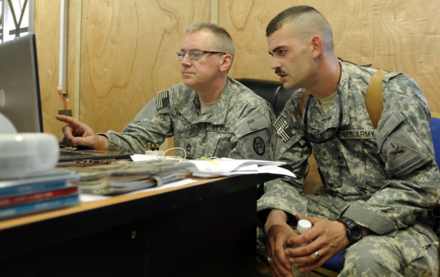 BAGHDAD - Sgt. 1st Class Cameron Mills (left), from Raleigh N.C., information operations non-commissioned officer in charge, Headquarters and Headquarters Company 30th Heavy Brigade Combat Team, asks questions of his counterpart Sgt. 1st Class David ...