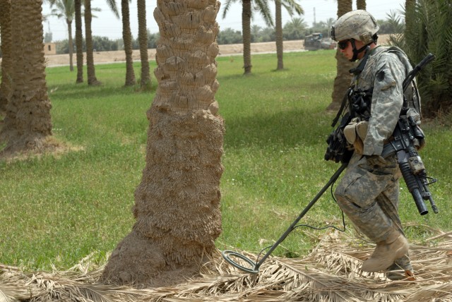 BAGHDAD - Cpl. Bryan Eveland, a cavalry scout team leader from Waterville, Pa., also assigned to C Troop, 2nd Squadron, 104th Cavalry Regiment, 56th Stryker Brigade Combat Team, walks with a metal detector to search for buried weapons and...
