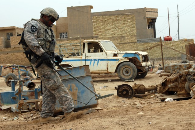 BAGHDAD – Spc. Ronnie Whitehurst, an infantryman from Pensacola, Fla., assigned to 56th Stryker Brigade Combat Team kicks away dirt while using a metal detector to find suspected weapons caches after a tip led his platoon to this area in Hay...