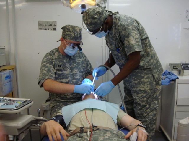 Capt. Daniel Roberts, an Army dentist, and Spc. Dan Curry, a dental hygienist, both from the 27th Brigade Support Battalion, 4th Brigade Combat Team, 1st Cavalry Division, remove four impacted wisdom teeth from a Long Knife Brigade Soldier. The...