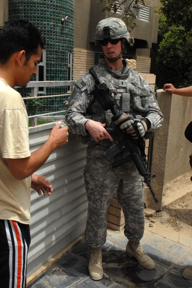 1st Lt. Christopher Miles of Midland, Texas, a platoon leader with 1st Battalion, 7th Artillery Regiment, 2nd Brigade Combat Team, 1st Infantry Division, hands out a tip card to an Iraqi man during a combined arms patrol in the Mutanabi...