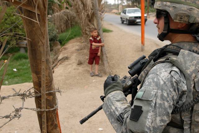Sgt. Eric Varner, a cavalry scout team leader from Chambersburg, Pa., assigned to C Troop, 2nd Squadron, 104th Cavalry Regiment, 56th "Independence" Stryker Brigade Combat Team, pulls security as an Iraqi child looks on during a micro-grant assessmen...