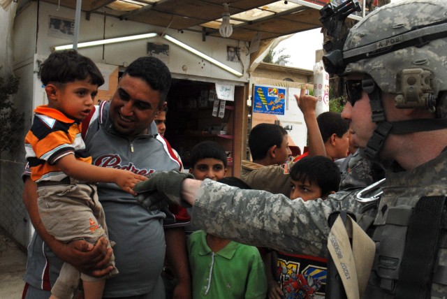 BAGHDAD- Spc. Ryan Chapman, Battery A, 1st Battalion, 7th Field Artillery Regiment, shakes hands with an Iraqi boy in the Mutanabi neighborhood of Baghdad May 8. "I have a soft spot for the kids, especially the little ones," said the native of Olathe...