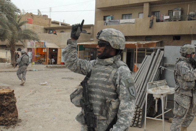 BAGHDAD - Staff Sgt. Trowny Alexis of Miami, signals for the Soldiers of Battery A, 1st Battalion, 7th Artillery Regiment, to mount up at the end of a patrol in a commercial district of the Mutanabi neighborhood of Baghdad May 8. The Soldiers arrived...