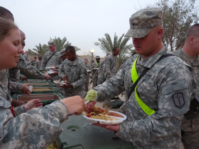 BAGHDAD - Spec. Bryan Bellamy (right), a heavy equipment operator with Company B, 46th Engineer Combat Battalion (Heavy), receives a helping of guacamole to complete his authentic Mexican dinner experience, 9 May.  Bellamy, from Abilene, Texas said, ...