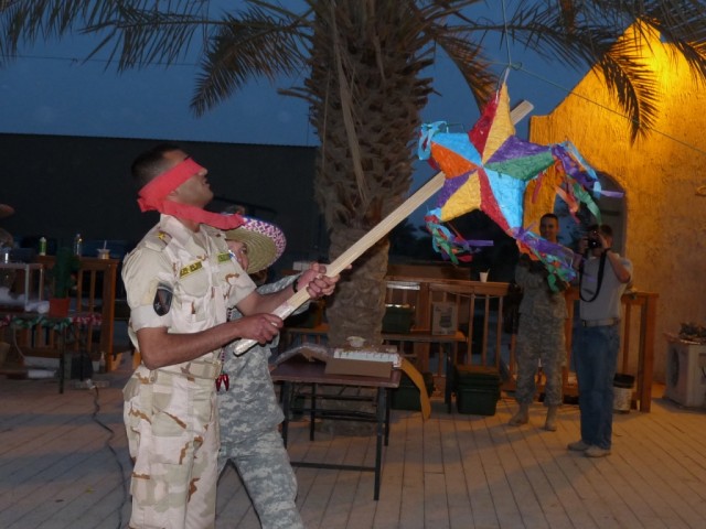 BAGHDAD - A blind-folded 1st Lt. Omar Mohammad Fadl, 6th Iraqi Army Engineer Regiment, is guided by a U.S. Soldier to a moving piñata at the "Cinco de Mayo" Engineer Call celebration held here, 9 May.  It took Lt. Fadl only two swings to bust open th...