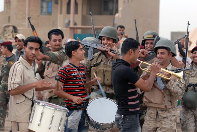 BAGHDAD - A small band, along with Soldiers of the 45th Iraqi Army Brigade, celebrate a goal by the home team during the Combined Forces Football Tournament, in the Salman Pak community, May 10. The game was met with enthusiasm and support from...