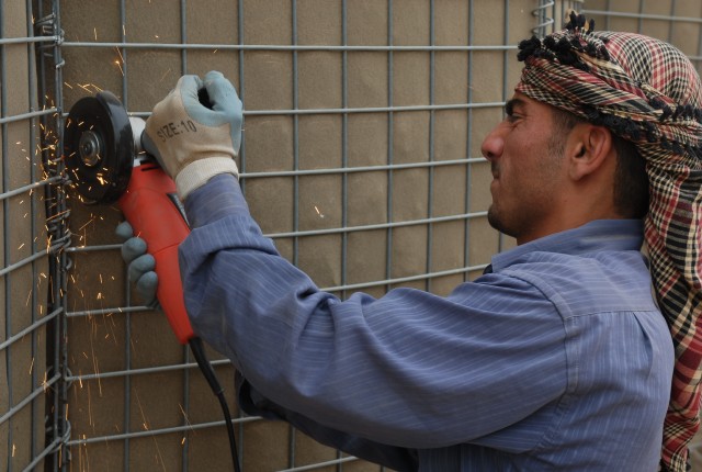 A worker cuts through and disassembles large barriers outside of the Emergency Response Unit in Kirkuk city, Iraq, May 9. The barrier removal project is taking place at different police stations through the city as security improves, along with marke...