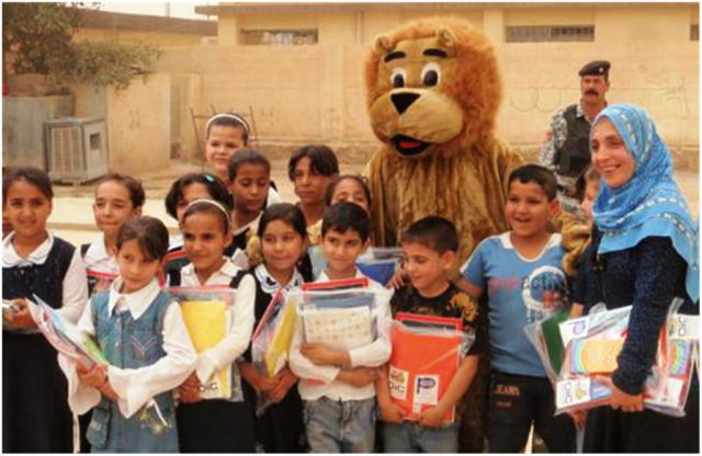 The "Lion of Kirkuk" stands amongst the children and teachers of the Halima al-Sadiya Primary School in the Qoria district of Kirkuk province, Iraq, May 6. The lion is actually an Iraqi Policeman that helped deliver much needed schools supplies to th...