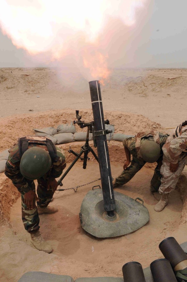 BAGHDAD - Iraqi Army soldiers assigned to 35th Iraqi Army Brigade, 9th Iraqi Army Division, duck down as a fiery blast comes from the mortar tube during a live fire exercise May 8.  During the three day training event, IA Soldiers demonstrated...