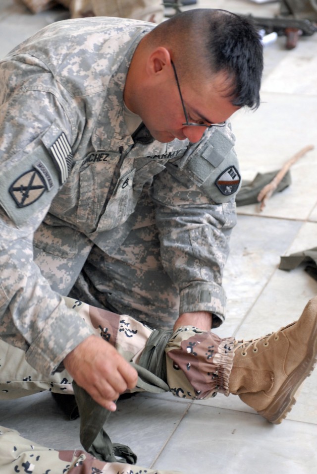 BAGHDAD - Staff Sgt. Adam Sanchez of the 225th Engineer Brigade, who hails from Pineville, La shows the students from the 11th Iraqi Army Engineer Regiment how to properly put on a dressing using the leg of one of his students.  Sanchez along with...