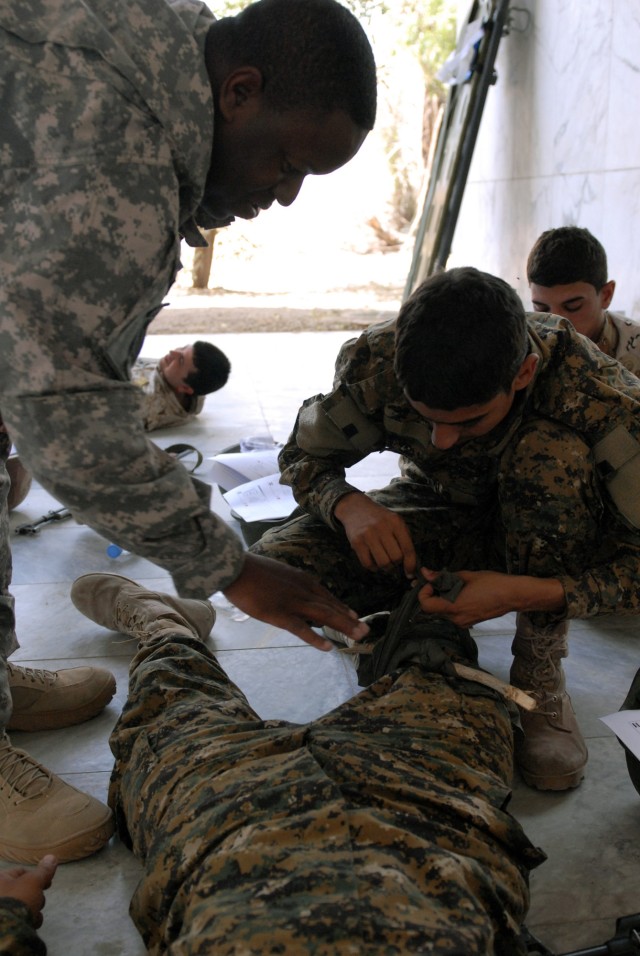 BAGHDAD - Alexandria, La., native Sgt. Mark Jackson, a member of the 225th Engineer Brigade instructs an 11th Iraqi Army Engineer Regiment Soldier how to properly apply an improvised tourniquet on a leg wound, May 13.  The application of a...