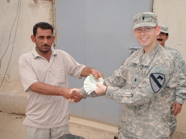 BAGHDAD-Tieton, Wash. native, 1st Lt. Nathan Kroger, shakes hands with Mohammed Jassim Almhinawi as he hands him $1,950 in cash as a micro grant May 10.  Lt. Kroger is the Fire Support Officer for Troop B, 1st "Garryowen" Squadron, 7th Cavalry...
