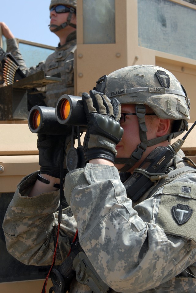 VICTORY BASE COMPLEX, Iraq - Spc. Brandon Barefield (left background), a Waco, Texas native and combat medic, mans the turret gun as Sgt. Mathew Wallace (right foreground), the sergeant of the guard from Florence, Texas, also originally a combat...