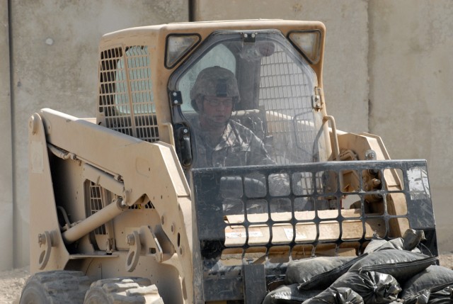 BAGHDAD - Pfc. Alexander Burton, a native of Kansas City, Mo., who is a combat engineer assigned to Company A, 2nd Battalion, 5th Cavalry Regiment, puts sand bags in place with his forklift, May 13, for the range that will be added to Joint...