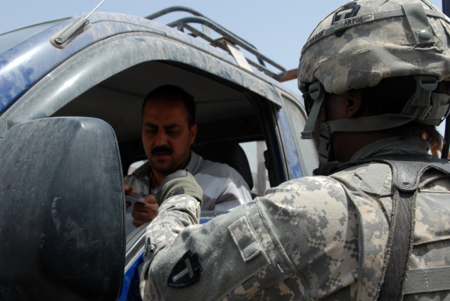 BAGHDAD - Spc. Tiffany Frenchwood, a logistical specialist assigned to Apache Troop, 1st Squadron, 124th Cavalry Regiment, hands back a local national's ID at a checkpoint at Victory Base Complex here, May 14. Frenchwood is one of a handful of...