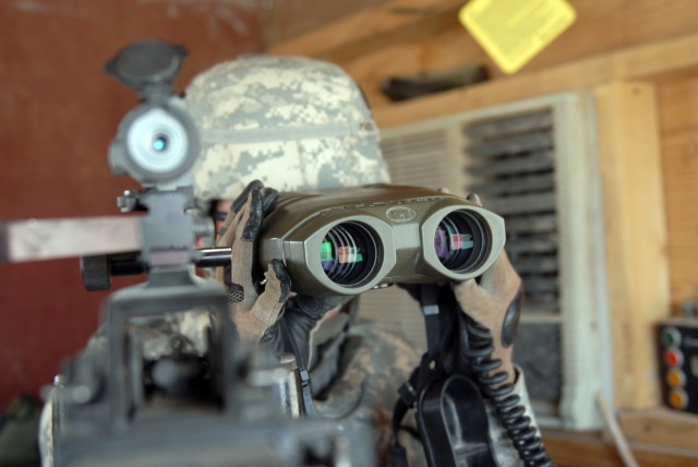 BAGHDAD - Spc. Janice Parisi, an intelligence analyst assigned to Apache Troop, 1st Squadron, 124th Cavalry Regiment, uses binoculars from her guard tower at Victory  Base Complex here to get a closer look at what's happening at her entry control...
