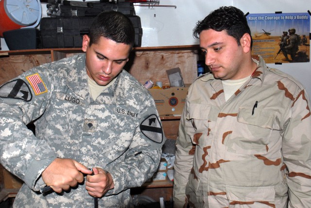 BAGHDAD - Spc. Jorge Lugo (left) assigned to Company C, Division Special Troops Battalion, 1st Cavalry Division, of San Juan, Puerto Rico, begins the process of cutting a fiber optic cable, May 13, so he can let Iraqi Army Sgt. 1st Class Saad...