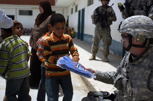 BAGHDAD-Hershey, Pa. native, Staff Sgt. Joseph Fimonetti, the fire support non-commissioned officer in charge, with 2nd Battalion, 112th Infantry Regiment, Multi National Division-Baghdad, hands out new book bags to Iraqi students at the Hamichun...