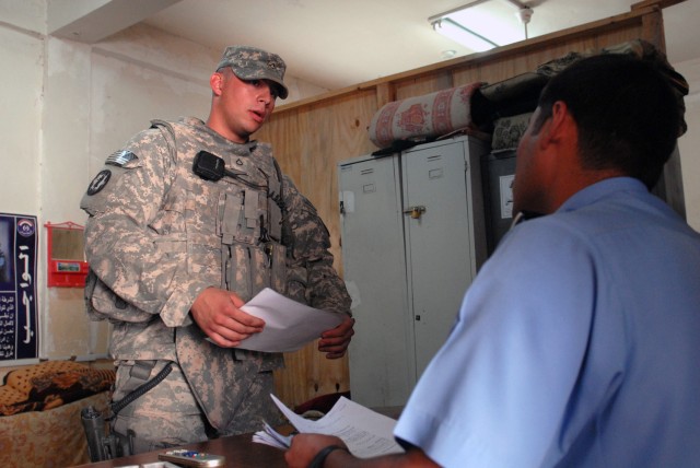 TAJI, Iraq - Pfc. Dustin Shuler, from Syracuse, N.Y., 591st Military Police Company, 93rd MP Battalion, 8th MP Brigade, checks numbers of detainees with Iraqi police at a station in Saab al-Bour, here, May 15. Soldiers of the 591st go over a...