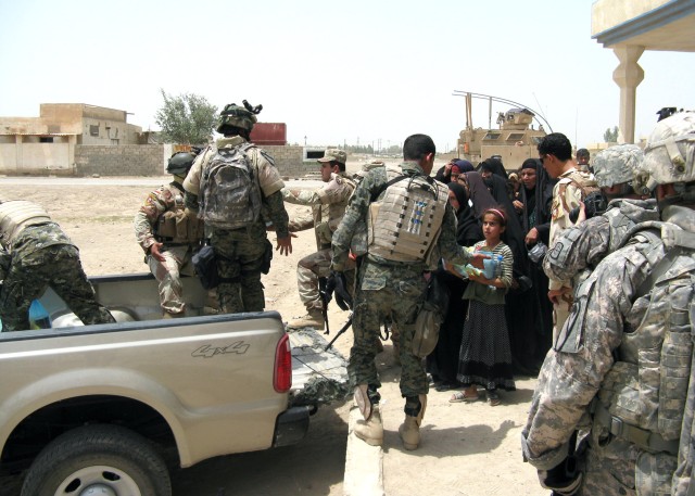 BAGHDAD - Members of the 1st Battalion, 24th Brigade, 6th Iraqi Army Division pass out humanitarian aid to the citizens of the Fira Shia area west of Baghdad May 17. Soldiers from the 2nd Battalion, 8th Cavalry Regiment, operationally attached to...
