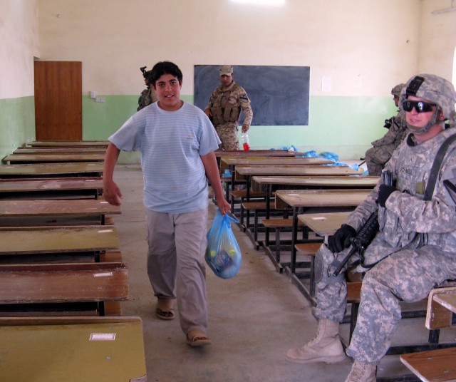 BAGHDAD - A smiling citizen of the Fira Shia area west of Baghdad walks past Pvt. Matthew Schnell, 2nd Battalion, 8th Cavalry Regiment, operationally attached to the 2nd Heavy Brigade Combat Team, 1st Infantry Division, Multi-National Division -...