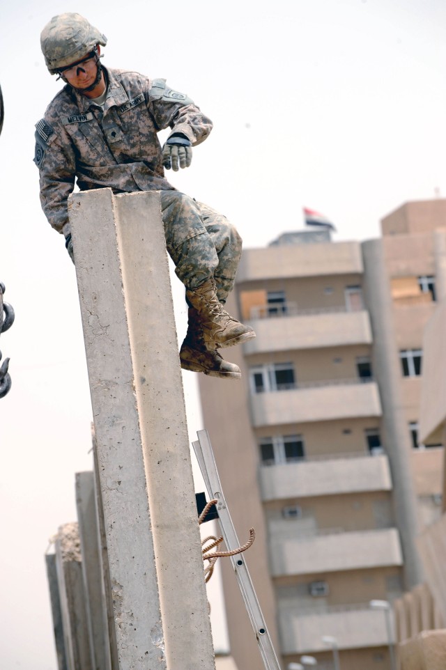 BAGHDAD - Spc. Brian Melvin, of Santa Cruz, Calif., assigned to Headquarters and Headquarters Company, Brigade Special Troops Battalion, 3rd Brigade Combat Team, 82nd Airborne Division, sits atop a concrete barrier after unhooking cables used to...