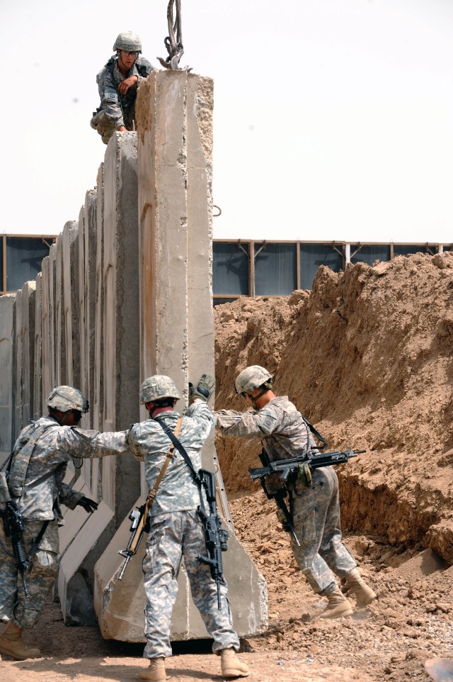 BAGHDAD - Paratroopers assigned to Headquarters and Headquarters Company, Brigade Special Troops Battalion, 3rd Brigade Combat Team, 82nd Airborne Division, guide a concrete barrier into position May 17 at Joint Security Station Loyalty, located...