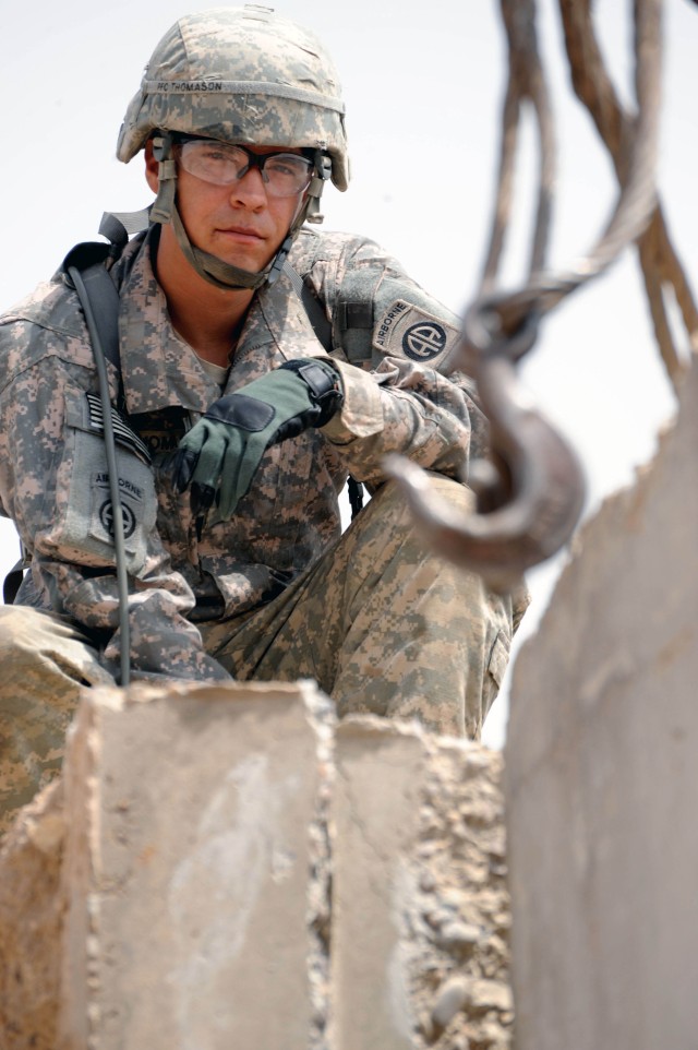 BAGHDAD - Spc. William Thomason, of Roanoke, Va., assigned to the Headquarters and Headquarters Company, Brigade Special Troops Battalion, 3rd Brigade Combat Team, 82nd Airborne Division, helps guide a concrete barrier into position during an...