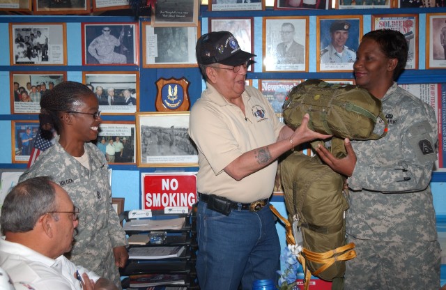 Master Sgt. Angela Bray, operations noncommissioned officer, chaplains office, U.S. Army North, hands a parachute and a reserve parachute to retired Sgt. 1st Class Marty Martinez. Martinez is the president of the Alamo Silver Wings Airborne...