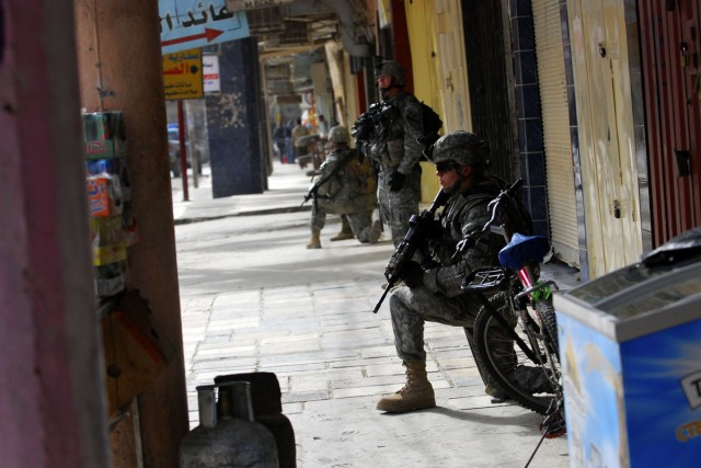 Soldiers from 2nd Platoon, B "Bulldog" Company, 3rd "Warhorse" Battalion, 8th Cavalry Regiment, 3rd Heavy "Greywolf" Brigade Combat Team, 1st Cavalry Division provide rear security as teams of Iraqi National Police and their fellow Bulldog Soldiers c...