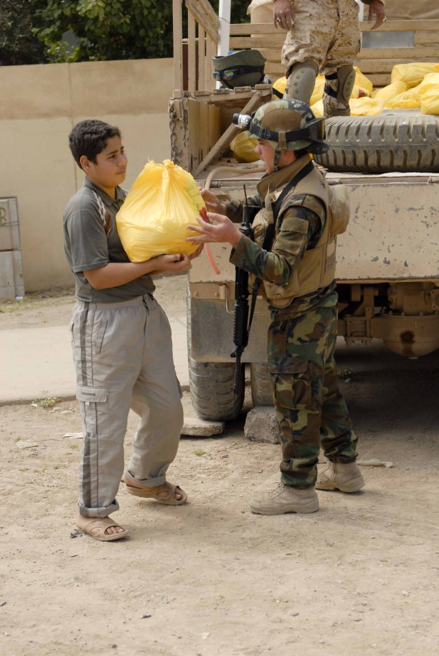 An Iraqi Army Soldier with 1st Battalion, 7th Brigade, 2nd Iraqi Army Division hands a bag of food to a young man that lives in the western Mosul neighborhood of Domiz. The Iraqi Security Forces in Ninewah province have taken command of projects such...