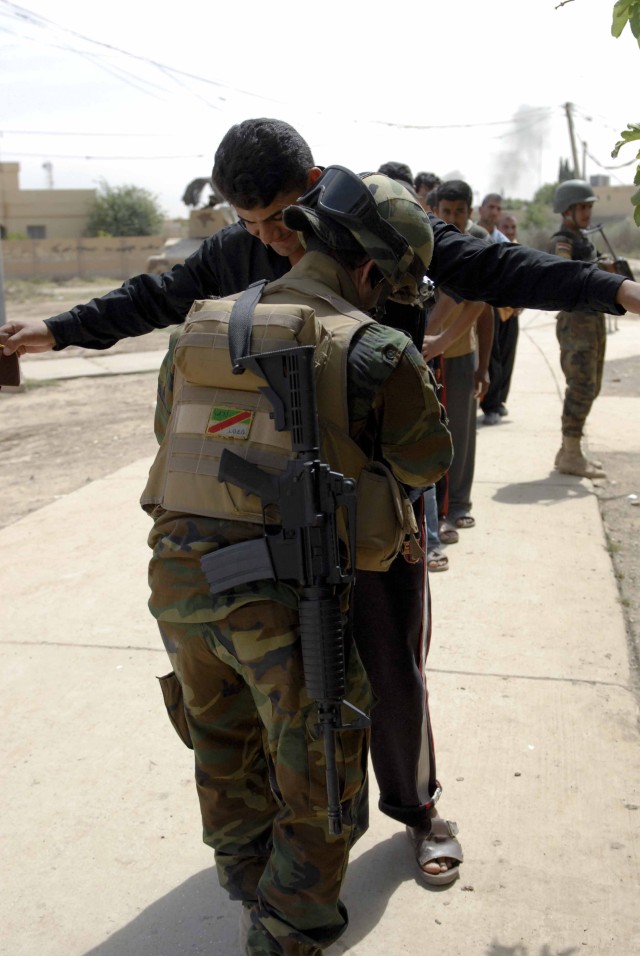 A Soldier with 1st Battalion, 7th Brigade, 2nd Iraqi Army Division searches a resident of the western Mosul neighborhood of Domiz before the man received his portion of dry goods during a humanitarian aid distribution May 9. The Iraqi Security Forces...