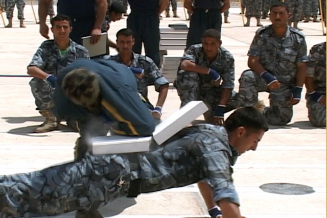 A combatives instructor demonstrates the use of martial arts taught to Iraqi Police trainees during their basic training by breaking a slab of concrete with his elbow on May 11, 2009 in Mosul, Iraq. This graduation marks the last class to graduate, f...