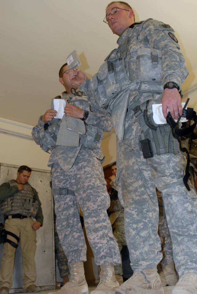 TAJI, Iraq - Pfc. Andrew Van Cleave (right), from Junction City, Kan., assigned to 591st Military Police Company, 93rd MP Battalion, 8th MP Brigade, talks about the Emergency Trauma Dressing at a first-aid class at the Tarmiyah Police Station here, M...