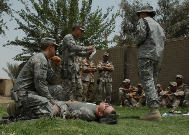 BAGHDAD- Using an interpreter (at right), medic Staff Sgt. Jose Martinez (center standing) of Lebanon, Pa., explains the care of a chest wound to Iraqi Army Soldiers May 17. Martinez used Spc. Dean Matthews (reclined) of Milton, Fla. and Cpl....