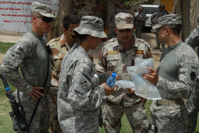 BAGHDAD- Medic Staff Sgt. Jose Martinez (at right), of Lebanon, Pa., hands bags of fluid to an Iraqi medic, May 17, after presenting a portion of the Army's Combat Lifesaver course to a class of Iraqi Soldiers. Martinez taught the class at Abu...