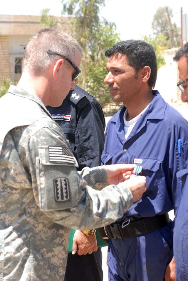 Lt. Col. Terry Cook, the commander of 3rd Battalion, 82nd Field Artillery Regiment, 2nd Brigade Combat Team, 1st Cavalry Division, awards the U.S. Army Achievement Medal to an Iraqi Policeman who works on maintaining police vehicles in Kirkuk...