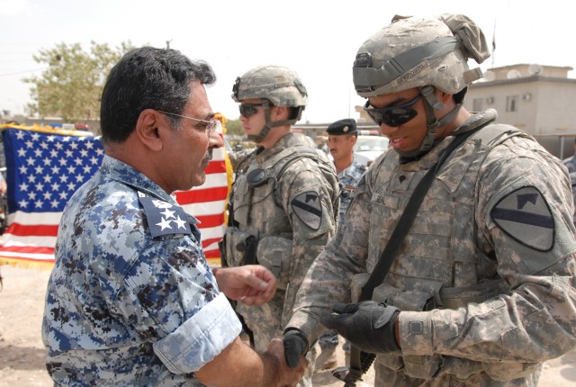 Brig. Gen. Khatad (left), the Iraqi Emergency Services Unit chief, gives Spc. Jonathan Real (right), a Bayamon, Puerto Rico, native and an artilleryman with Battery B, 3rd Battalion, 82nd Field Artillery Regiment, 2nd Brigade Combat Team, 1st...