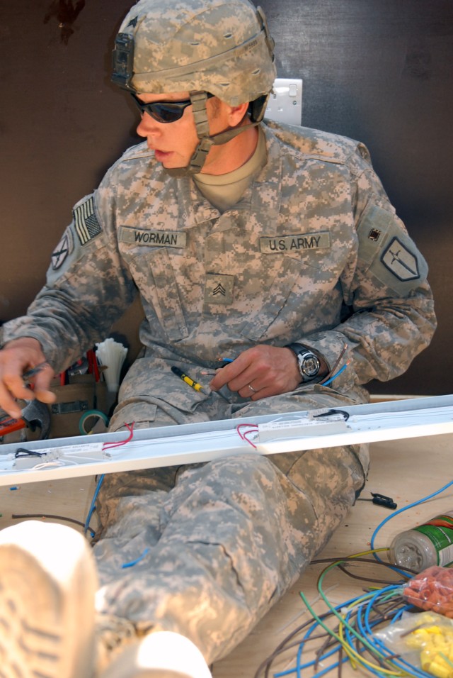 BAGHDAD - Sgt. Michael Worman, of Nampia, Idaho, connects electrical wires inside an interior light fixture before it is installed in a completed B-Hut at Combat Outpost Carver, May 18. Engineers with the 46th Engineer Battalion, 225 Engineer Brigade...