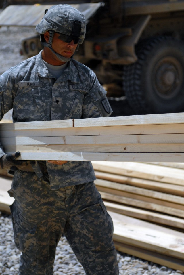 BAGHDAD -Spc. Joseph King, of Monterey, Calif., a member of the 46th Engineer Battalion, 225th Engineer Brigade, 1st Cavalry Division, carries wood for wall studs to a cut station so they can be sliced down to the correct length. King and his fellow ...