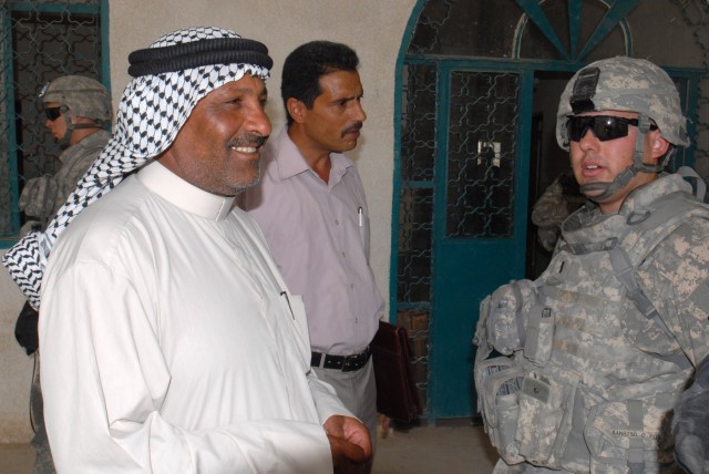 BAGHDAD - 1st Lt. Michael Neel of Glendale, Calif., an armor officer assigned to Co. A, 2nd Bn., 8th Cav. Regt., speaks to Sheikh Saad Turky Hassan (left) and Kadhum Noman (center), a linguistics teacher, at a school in the village of Firra Shia...