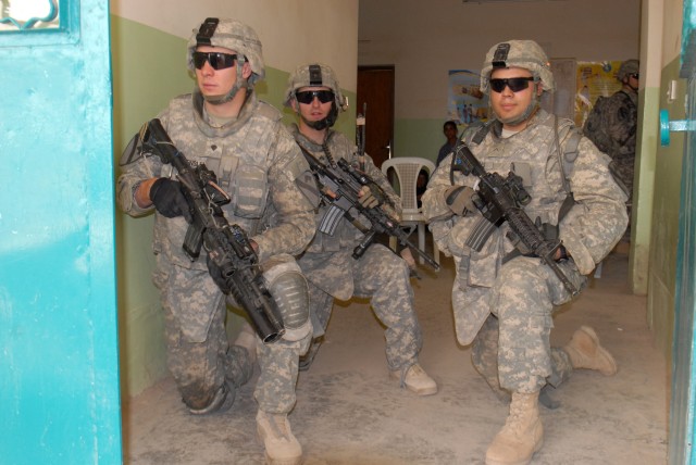 BAGHDAD - Spc. Jason Hensley of Littleton, Colo., Cpl. Mark Rominger of Dry Fork, Va., and  Pvt. Adolfo Torres of Bedford, Texas, all assigned to Co. A, 2nd Bn., 8th Cav. Regt., perform security duties at a school in the village of Firra Shia west...