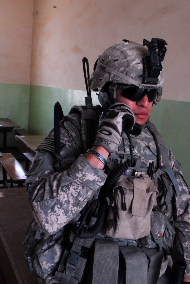 BAGHDAD - Staff Sgt. Valentin Arreola, an infantryman assigned to Co. A, 2nd Bn., 8th Cav. Regt., keeps in touch with his Soldiers while conducting security at a school in the village of Firra Shia while Iraqi Soldiers dispense bags of food during...