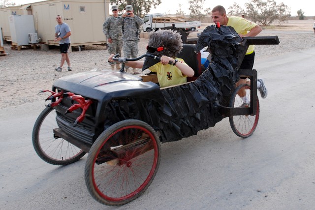 Pfc. David Taylor pushes while Sgt. Amber Harvey steers in a sprint for the finish line May 8 at the first Contingency Operating Base Speicher Soap Box Derby. Although it placed last in the time trials, the Network Extension Platoon, Company C,...