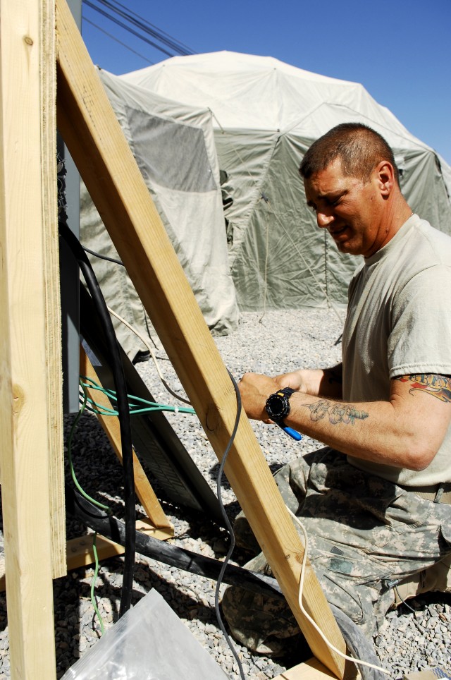 Joint Sustainment Command-Afghanistan engineer, 1st Lt. Alex R. Chester III, installs electrical wiring while building the 143d Expeditionary Sustainment Command compound at Kandahar Airfield. Chester utilizes his civilian engineering skills to...