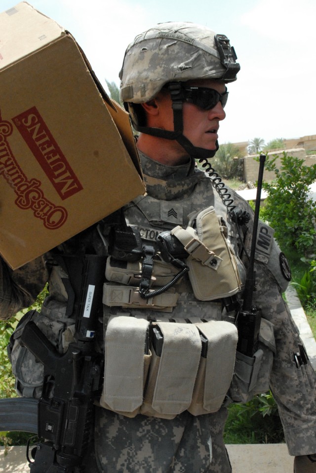 BAGHDAD - Sgt. George Talkington, a native of Las Cruces, N.M., a military policeman assigned to the 591st Military Police Company., 93rd MP Battalion, 8th MP Brigade, takes a box of muffins to a chicken farmer who asked for assistance in the Abu...